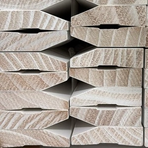 Stack of prime coated timber half splayed architraves or skirting boards, which is a type of moulding installed around door frames. A half splayed design means it has angled edges.